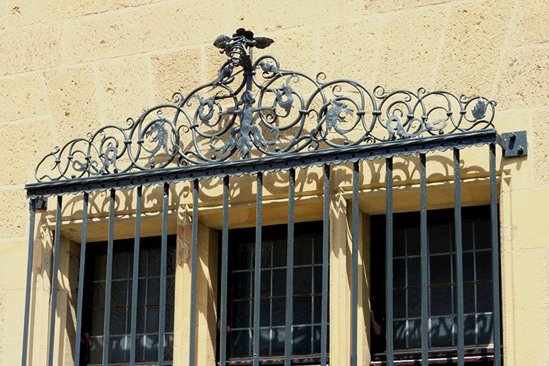 Besonders kunstvoll gestaltet ist die Bekrönung des schmiedeeisernen Gitters vor dem unteren Fenster der Giebelseite des Sakristeihauses, das kürzlich restauriert wurde. Allerdings wird es durch den unmittelbar darunterliegenden Gemeindesaal großenteils verdeckt. (c) privat